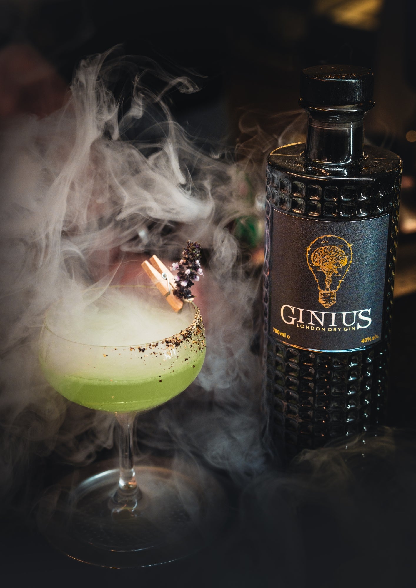  'GINIUS' next to a cocktail with smoke effects on a dark background from flavour blaster.